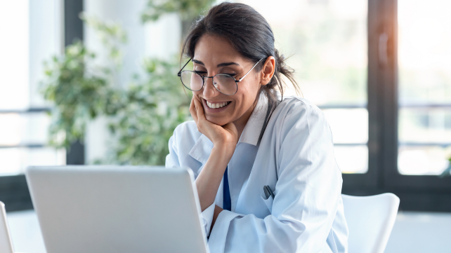 Picture of provider smiling at laptop using software for optometrists 