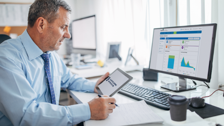 Man looking at tablet near desktop computer