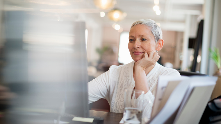 Woman smiling looking a a desktop computer 