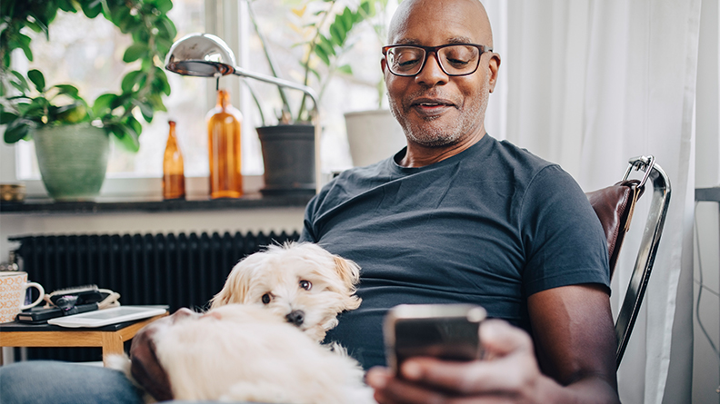 Man smiling at this phone with dog on his lap