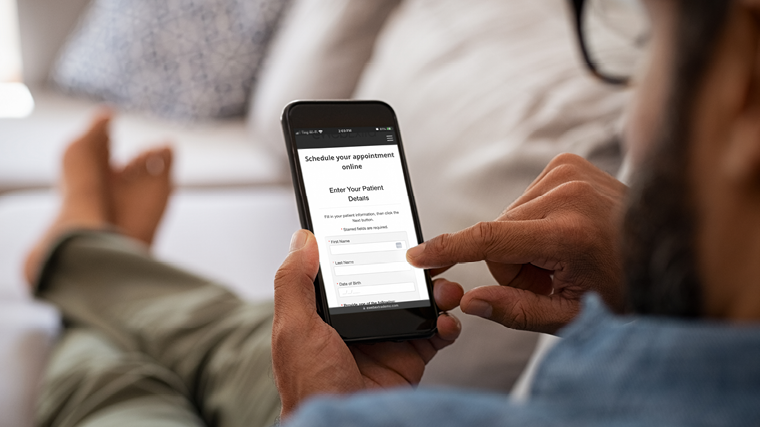 Man relaxing at home booking an appointment on his smart phone